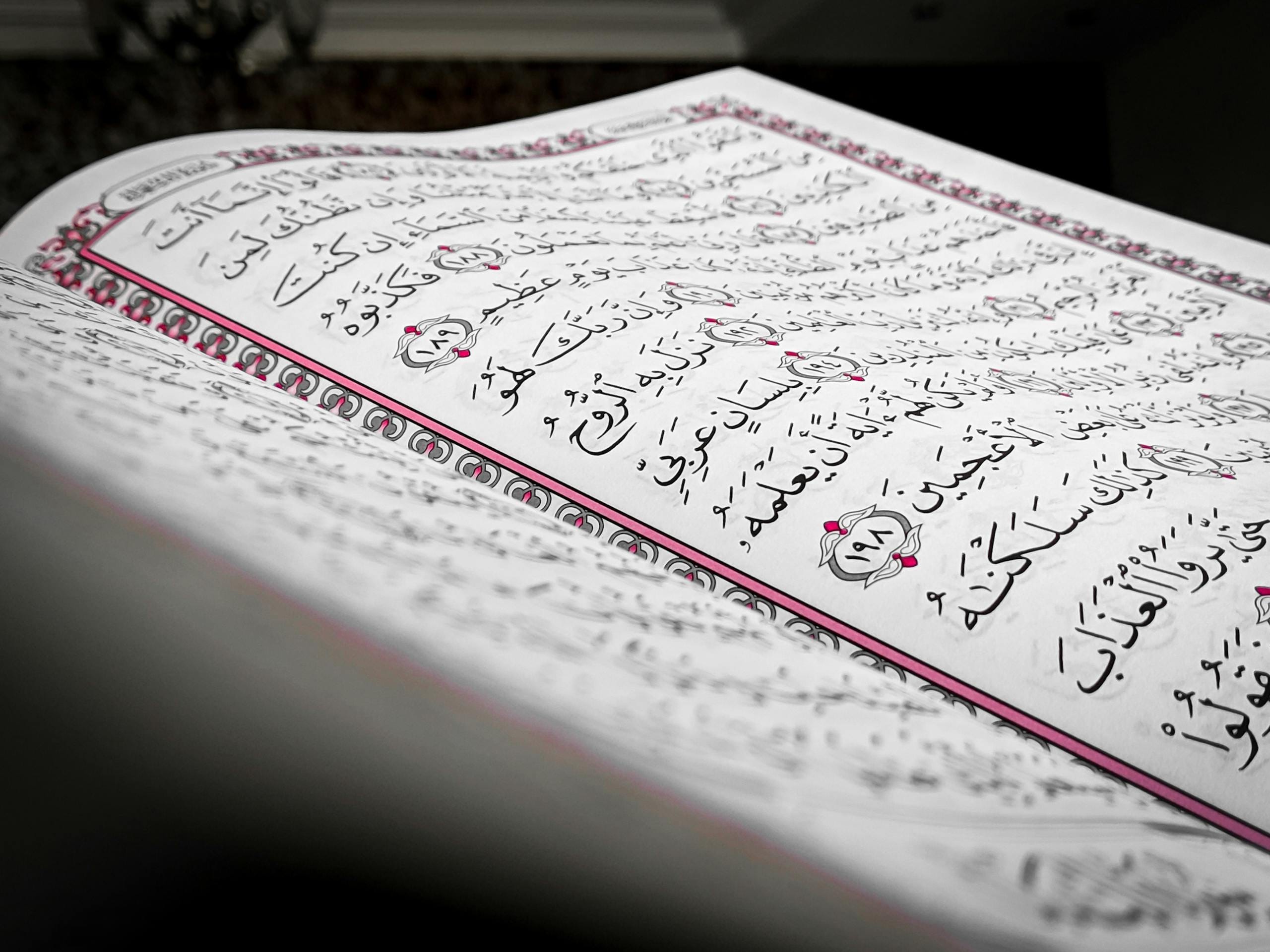 Quran Tafseer Online Classes 5 Detailed close-up of an open book showcasing Arabic script, featuring ornamental design and elegant calligraphy.