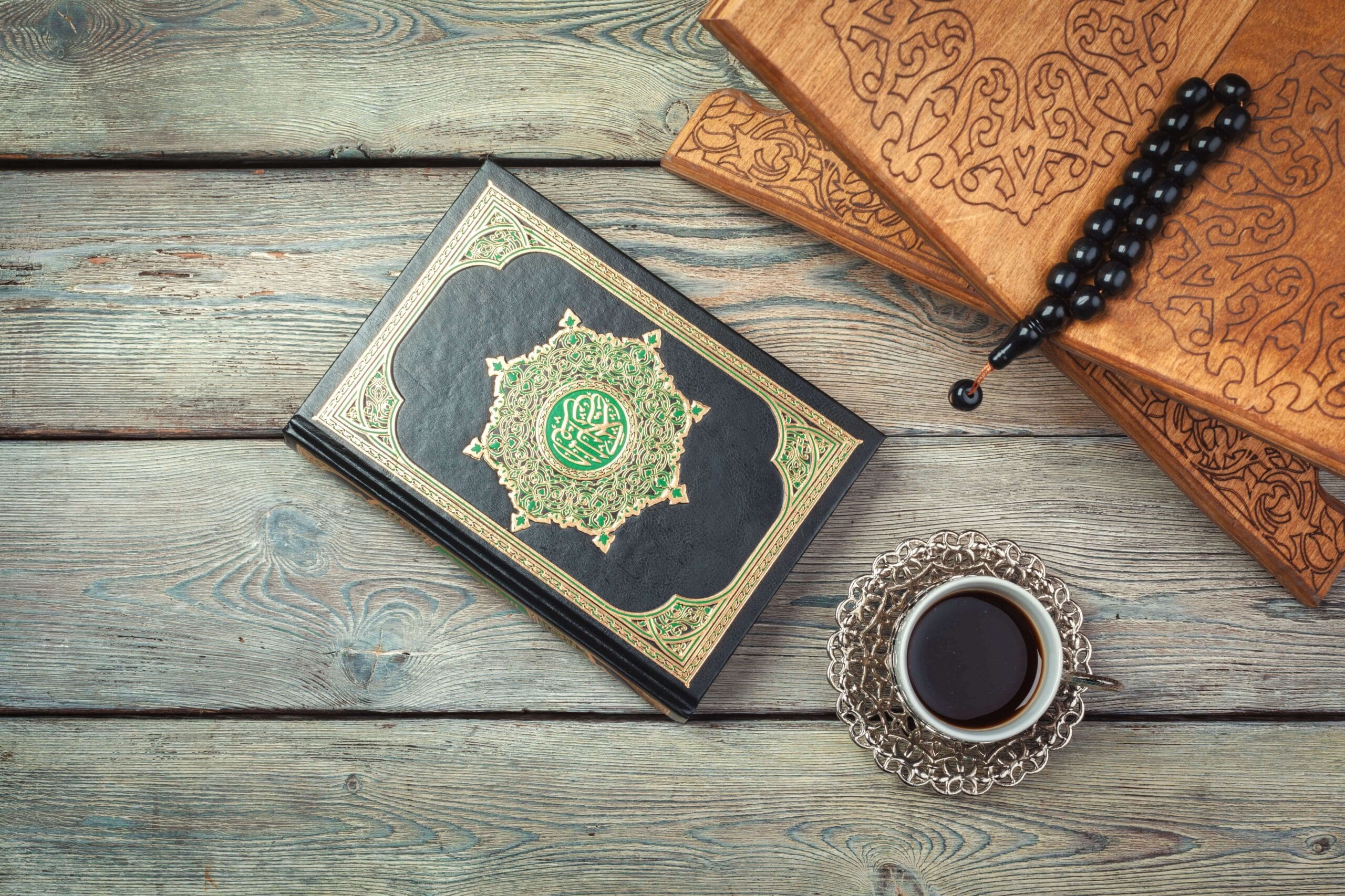 Home 11 A top-down view of a Holy Quran, a cup of coffee, and a tasbih on a rustic wooden table.