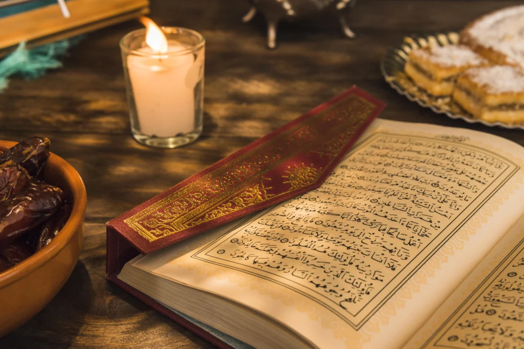 Online Quran Memorization Course 6 n open Quran with a decorative bookmark rests on a wooden table next to a lit candle, a bowl of dates, and a plate of pastries.