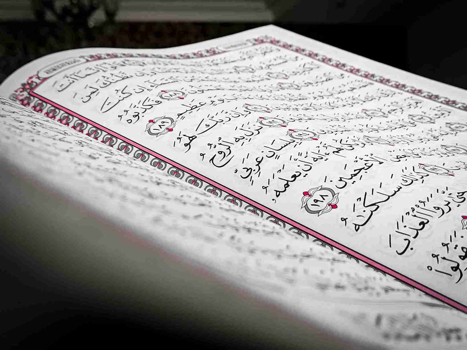 Close-up of open book with Arabic calligraphy and decorative ornamental designs