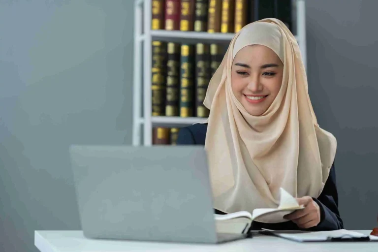 Muslim woman studying with laptop and book during Online Quran Classes in Green Bay