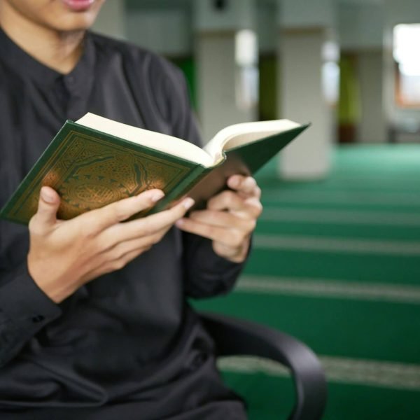 Deepen Your Faith with Online Quran Classes – Al-Tahoor Quran Institute Young Muslim man in black attire reading the Quran inside a mosque with a green prayer carpet. This image symbolizes Islamic devotion, Quran recitation, and spiritual reflection in a peaceful environment. Al-Tahoor Quran Institute (www.altahoorquraninstitute.com) offers online Quran classes to strengthen faith and knowledge.